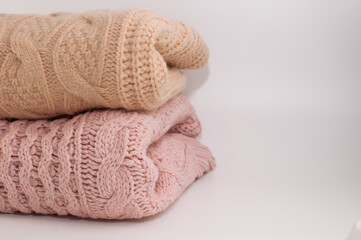two knitted sweaters in beige and pink colors on a white background with space for text