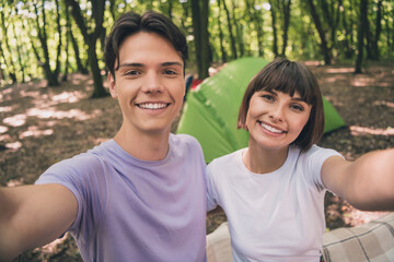 Photo portrait young couple taking selfie smiling in green summer forest near tent camping
