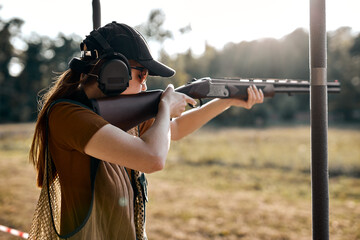 Young caucasian female on tactical gun training classes. Woman with weapon, wearing cap, protective...