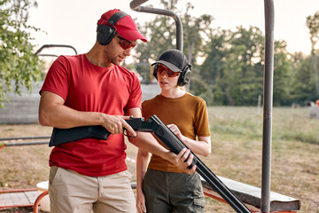 handsome caucasian man and young woman checking details of weapon before training loading gun...