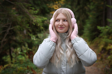 Young beautiful woman wearing warm earmuffs in forest