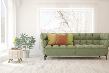 Fototapeta premium White living room with sofa and winter landscape in window. Scandinavian interior design. 3D illustration