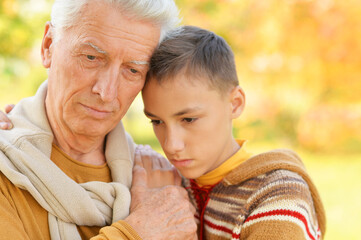 Portrait of sad grandfather and grandson hugging