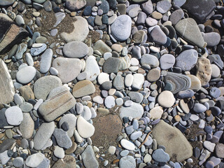 Sea stones background with small pebbles or stone in garden or in the seaside or on a beach. A close up view of rounded smooth polished pebble stones