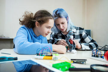 Two teenager girl at robotics school makes robot managed from the constructor, children learn robot...