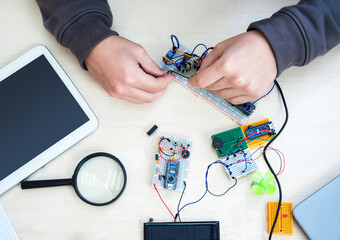 Close-up hands with electronics development board. Robot microcontrollers board and equipment in robotics laboratory school.