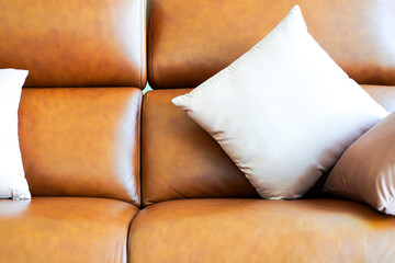 Light color square pillow on the luxury classic vintagae orange brown genuine leather sofa.