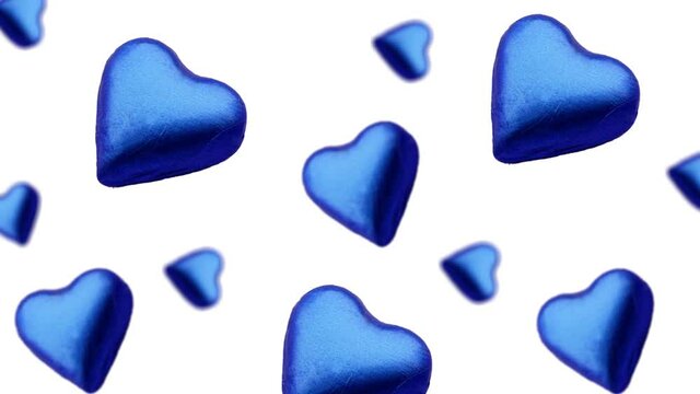 A stream of many different diameters heart shape wrapped colorfulchocolate candy flying on a white color background.Romantic template Love concept for mother's, St. Valentine's and women's 