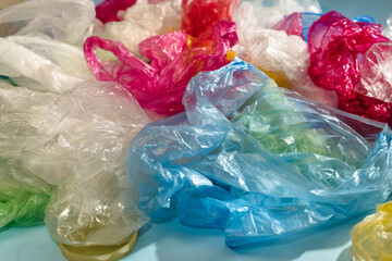 Fototapeta premium Colored plastic disposable bags in a pile of garbage. Environmental pollution. Environmental problem, global warming, waste sorting. World ecology problem, landfill.