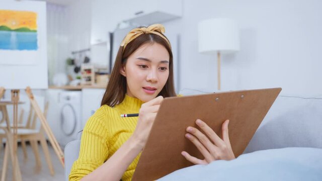 Asian woman artist drawing picture on painting board in living room. 