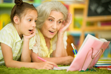 Grandmother with cute little girl doing homework together
