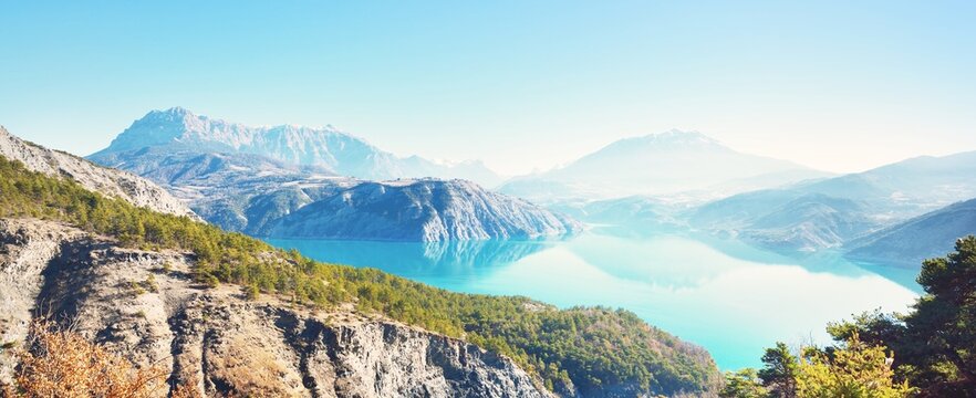 Panoramic view of the mountain lake Lac de serre-poncon in French Alps on a sunny day. Clear blue sky, still water. Travel destinations, tourism, landmark, nature, Christmas vacations in France