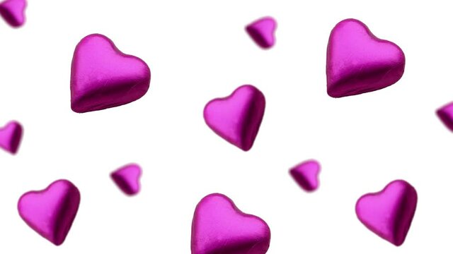 A stream of many different diameters heart shape wrapped colorful chocolate  candy flying on a white color background.Romantic template Love concept for mother's, St. Valentine's and women's  Day