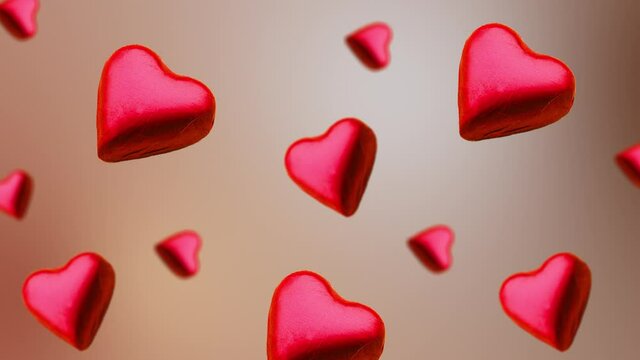 Flying A heart shape wrapped chocolate candy flying and wiggle of different diameters on the natural beige background. Concept of day of St. Valentine's, weddings, birthday and other holidays