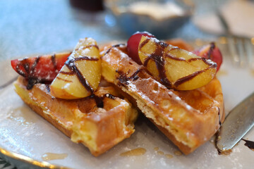Dessert topped with various fruits and sauces on waffles
