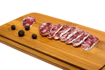 Smoked sausage cut on a wooden board with peppers isolated on white background