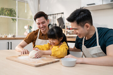 Fototapeta premium Asian attractive LGBTQ gay family teach girl kid making yeast dough. 