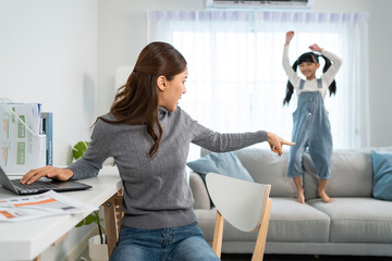 Asian business woman work at home with young kid daughter play around. 