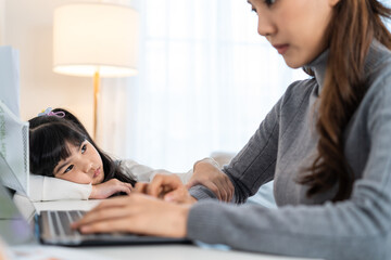 Asian young kid daughter feeling sad and need to play with busy mother. 