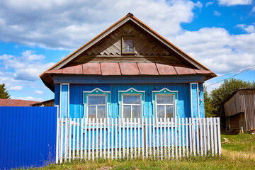 A traditional old wooden house with a front garden. Summer view.