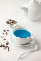 Thai blue Anchan tea in a white cup and teapot on a wooden background.