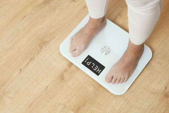 Feet Of A Woman Stepping On A Scale Indoors, Room For Text. Overweight Problem