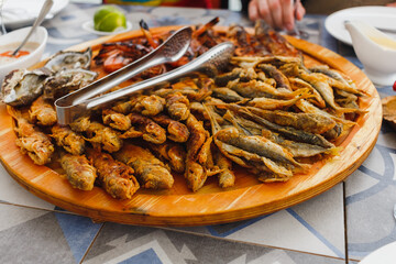 Wooden plate with fried fish. Fish dishes. Mediterranean cuisine.