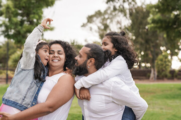 Happy indian parents having fun at city park with children - Family love