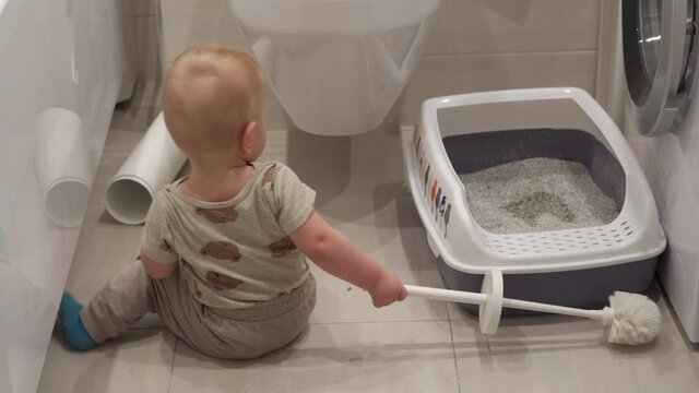 Cute baby crawling on the floor, 10 month old baby boy exploring cat litter box in the bathroom. High quality 4k footage
