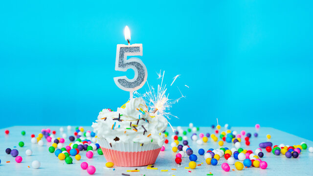 Beautiful congratulations on the birthday of a five-year-old child on a blue background, a card for 5 years happy birthday copy space. Festive background with cream cake