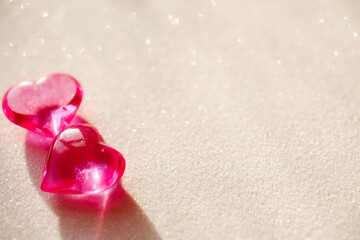 Two pink glass hearts on the white glitter background, valentine's day concept, selective focus. 