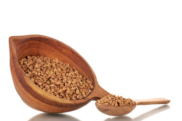 Uncooked organic buckwheat groats with wooden cup and spoon, close-up, isolated on white.