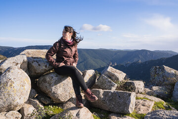 Woman sitting on the hill of a mountain contemplating the landscape