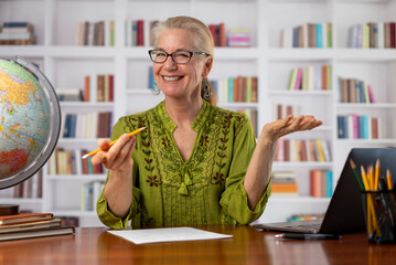 Portrait of remote teacher woman talking looking at webcam point of view in home office library. Teaching students doing video chat. Remote learning concept.
