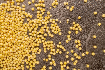 Raw organic millet groats on a metal tray, macro, top view.