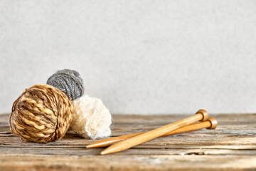 Balls of wool yarn and wooden knitting needles on the table. Hobby craft background with space for text. Concept of knitting, needlework.