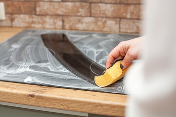 A young woman is cleaning an induction electric hob. Cleaning in the kitchen. Electric oven...