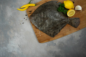 Raw flounder fish with spices. Seafood on a black stone background. Top view.