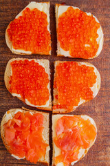 Bruschetta with red caviar and fish on a wooden board.