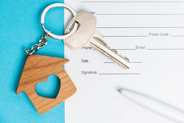 New key with a brel house on a blue background with documents and pen. Flat lay. Mortgage and lending concept