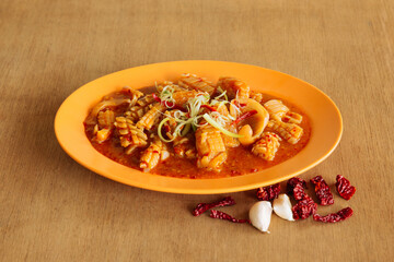 Cuttlefish with Satay Sauce in orange plate isolated on wood background top view