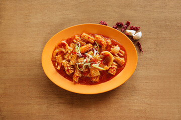Cuttlefish with Satay Sauce in orange plate isolated on wood background top view