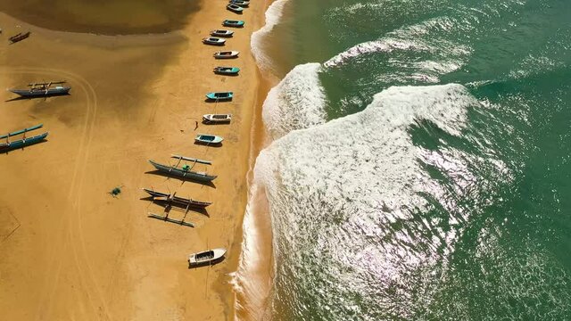 Top view of tropical sandy beach with fishing boats and a blue ocean. Arugam Bay, Sri Lanka.