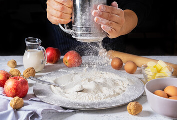 Ingredients for cooking an apple pie and woman hands with flour sifter