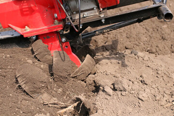 Garden tiller for cultivating field, loosens soil. Handheld motor plow