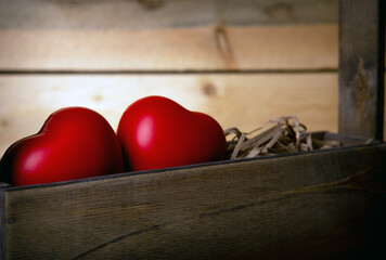 two large red hearts in the basket on a wooden background close up