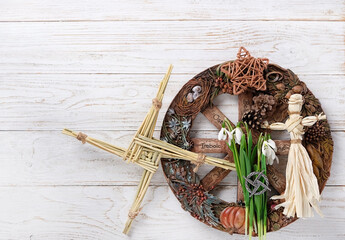 Wiccan altar for Imbolc sabbat. pagan festive ritual. Brigid's cross amulet of straw, wheel of the year, snowdrops, witchcraft doll on wooden table. Imbolc holiday, spring equinox. top view - obrazy, fototapety, plakaty