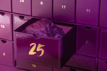 Violet advent calendar. In the advent calendar, cell number 25 is open, a Christmas present. A gift in wrapping paper inside an advent box.