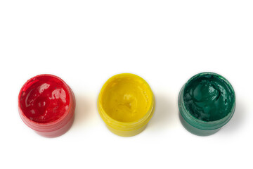 Jars of red, yellow and green gouache on a white isolated background. Traffic light concept, children's creativity. Bright colours.