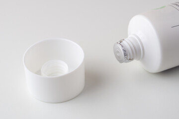 Sealed white tube of ointment and cap on a white background. A tube of cream covered with protective foil. The cap removed from the tube of cream.